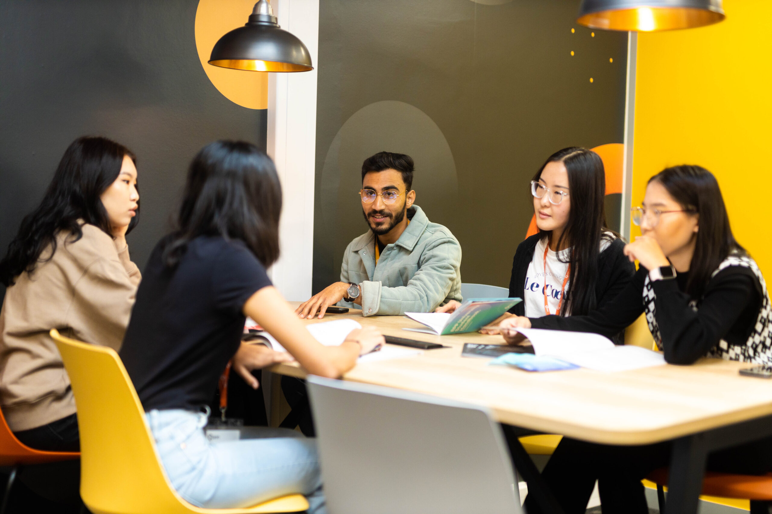 Students taking part in a group study discussion around a table with books and notes.